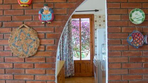 A brick-walled hallway with a wooden door, decorative plates, and a woven basket. - Veranda Piau  (Tertenia)