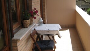 En balkon med et bord, stole, en potteplante og en lygte.