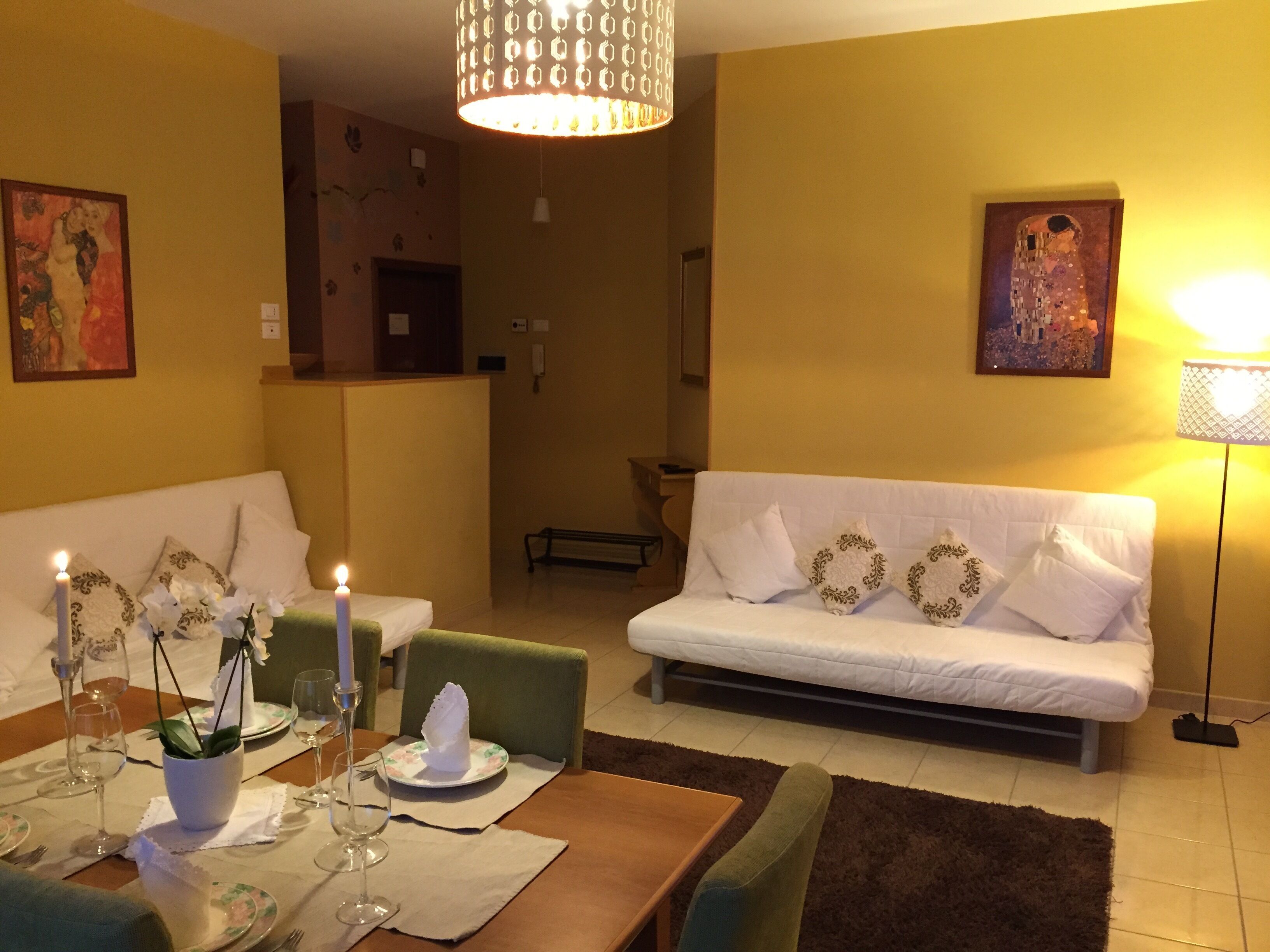 Un comedor con una mesa dispuesta para dos personas, un sofá y un banco.