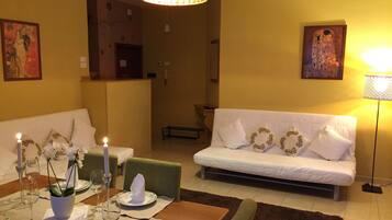 Un comedor con una mesa dispuesta para dos personas, un sofá y un banco.