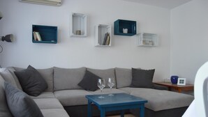 Una sala de estar moderna con un sofá seccional gris, una mesa de centro azul y estanterías empotradas con libros y objetos decorativos.