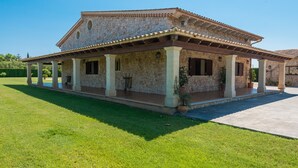 A stone building with a covered patio and a lawn in front.