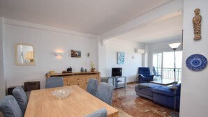 A spacious living area with a wooden dining table, grey upholstered chairs, a blue sofa, and a television on a stand. - Ref: 237 Beachfront apartment in Carvajal with amazing sea views (Fuengirola)