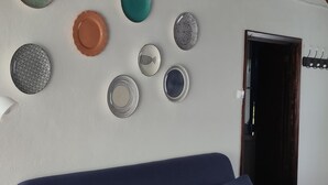 Una sala de estar moderna con un sofá azul, platos decorativos en la pared y una lámpara de techo tejida.