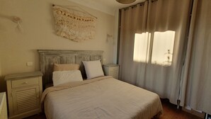 A bedroom with a large bed, two bedside tables, a headboard, and a window with curtains. - Charming Vendée house with small enclosed garden (Olonne-sur-Mer)