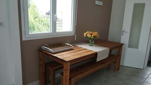 A wooden table with a tray and a vase of flowers, a bench, and a door with a sign above it. - Charming Vendée house with small enclosed garden (Olonne-sur-Mer)