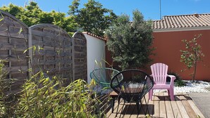 A wooden deck with two chairs, a small table, and a wooden fence. - Charming Vendée house with small enclosed garden (Olonne-sur-Mer)