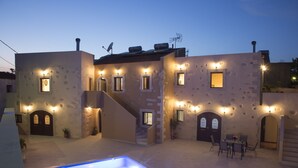 Un edificio con varias ventanas y puertas, una piscina y mobiliario exterior.