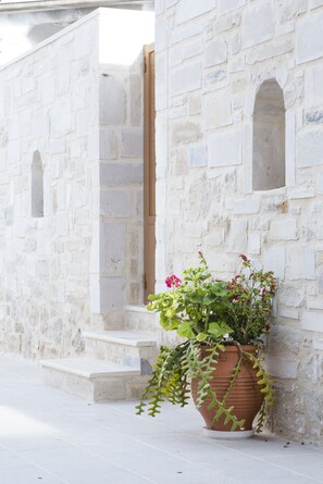A stone building with a large terracotta pot with plants on the steps.