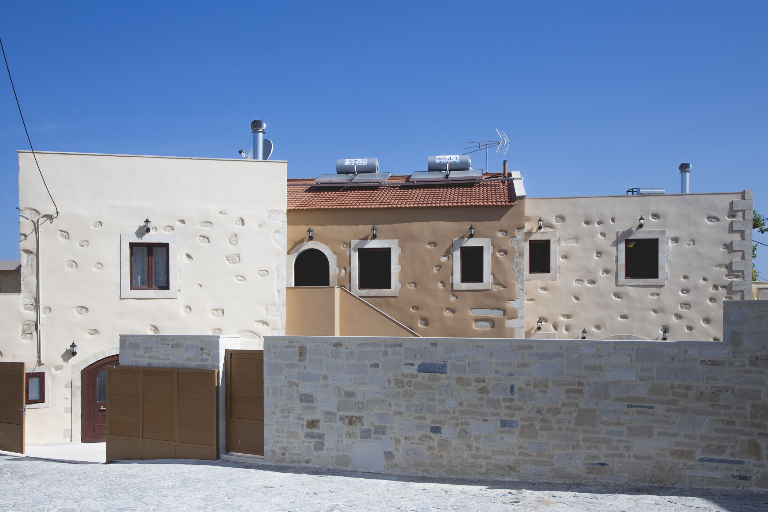 A building with a stone wall, a tiled roof, and a flat facade.