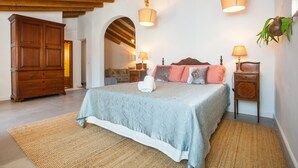 Een slaapkamer met een groot bed, een houten garderobe en twee nachtkastjes met lampen.