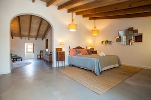 A bedroom with a bed, bedside lamps, a mirror, and a wooden ceiling.