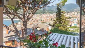 A balcony with a view of a coastal city, a large tree, and red flowers. - The suspended ship in Rapallo. Gorgeous apartment with a view of Portofino. (Rapallo)