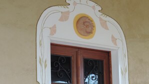 A wooden double door with decorative ironwork, set within a white archway with a floral motif. - Isolated on hill, flat with private terrace among romanesque art,quiet,nature. (Cocconato)
