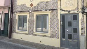 A building with a tiled facade, a sign reading "Casa de Santo Antonio," and a gray door with a window.