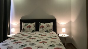 A bedroom with a bed, two bedside lamps, and a nightstand.