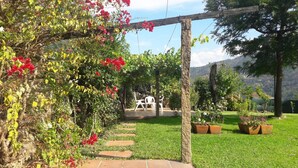 Ein Garten mit einer Pergola, einem Weg und einer Sitzgelegenheit.