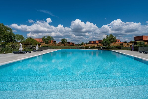 Ein rechteckiger Swimmingpool mit klarem, blauem Wasser, umgeben von einer gepflasterten Liegefläche.