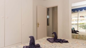 A bedroom with a bed, a wardrobe, a door, and a mirror reflecting a balcony.