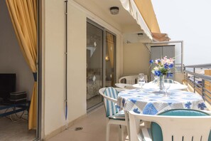 A balcony with a table and chairs, a TV, and a sliding glass door. - Santa Maria 65 - Two Bed (Costa Adeje)