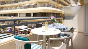 A balcony with a table, chairs, and a bottle of champagne.