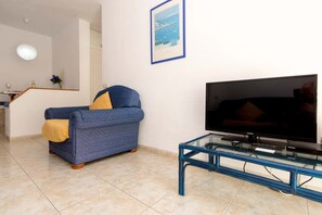 A living room with a sofa, a television on a glass table, and a framed picture on the wall. - Santa Maria 65 - Two Bed (Costa Adeje)
