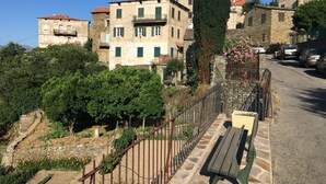 A stone building with a balcony and a garden with flowers and a bench. - Village house in the heart of Sorio (Sorio)