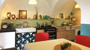 A kitchen with a dining area, featuring a tiled backsplash, a stove, a sink, and a dining table with chairs. - Village house in the heart of Sorio (Sorio)