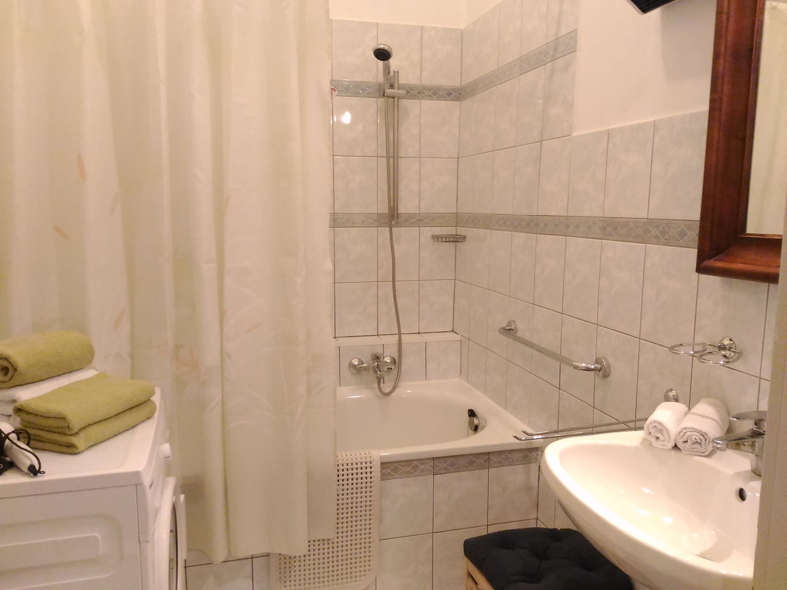 Kylpyhuoneessa on kylpyamme, suihku ja pesuallas. Pyyhkeet ja hygieniatuotteet ovat näkyvillä.