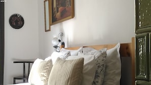 Un lit bien fait, agrémenté de plusieurs oreillers et doté d’une tête de lit. Une petite table avec une lampe se trouve à côté du lit.