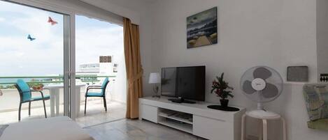 Une chambre d’hôtel moderne dotée d’un balcon, d’un téléviseur à écran plat, d’un ventilateur sur pied et d’un tableau au mur.