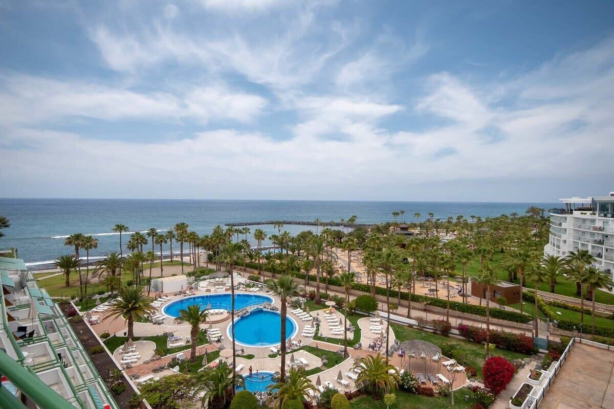 A resort with a large pool, palm trees, and a view of the ocean.