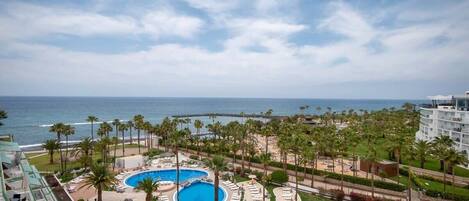 A resort with a large pool, palm trees, and a view of the ocean.