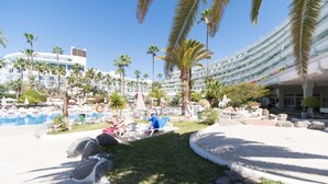 Ein Resort mit Pool, Palmen und einem modernen Gebäude mit Balkonen.