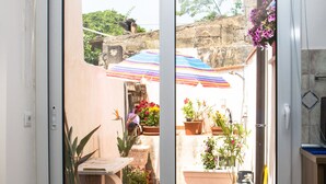 Eine Glastür führt zu einer Außenpatio-Terrasse mit Pflanzgefäßen und ein Kachelboden.