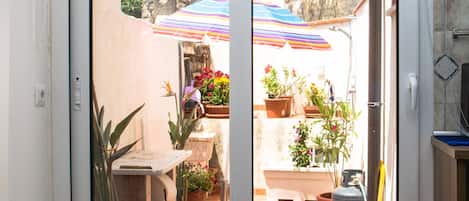 A sliding glass door leading to an outdoor patio area with potted plants and a tiled floor.