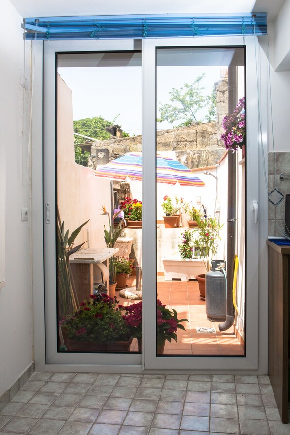 A sliding glass door leading to an outdoor patio area with potted plants and a tiled floor.