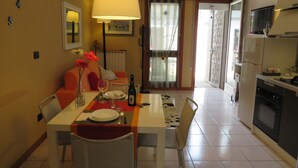 Un comedor con una mesa dispuesta para dos personas, un sofá y una cocina al fondo.