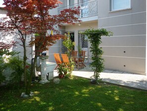 A courtyard with a table and chairs, surrounded by plants and a small tree with red leaves. - Casa Giulia independent apartment (Mira)