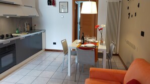Una cocina moderna con comedor, que incluye una mesa para dos personas, copas de vino y una botella.