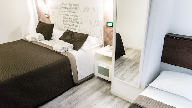 A hotel room with a bed, a nightstand, and a mirror. - NASONI DI ROMA COLOSSEUM APPARTAMENT  (until 33 people) (Roma)