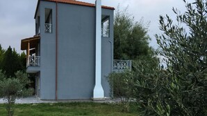 Ein modernes Gebäude mit einer grauen Fassade, einem roten Ziegeldach und einem Balkon mit Holzbalkon.