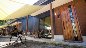 An outdoor seating area with a canopy, wooden chairs, and a table. - RiverStone MinakamiCampsite (Minakami)