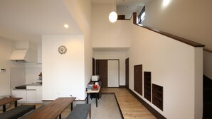 A spacious living area with a kitchen, dining table, benches, and a staircase. - RiverStone MinakamiCampsite (Minakami)