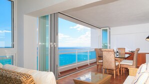 Ein Balkon mit Blick auf das Meer, Korbmöbel und ein Tisch mit Glasplatte.