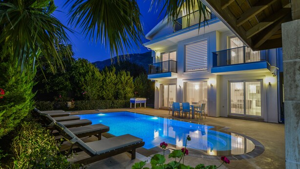 A modern two-story house with a swimming pool, outdoor seating, and a view of the mountains. - luxury villa for rent city D (fethiye)
