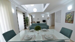 A modern dining area with a glass table, teal chairs, and a central plant. - luxury villa for rent city D (fethiye)