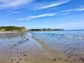 A beach with clear skies, calm water, and a distant rocky coastline. - Gower, Oxwich, Amazing Views, Sleeps 4 (Oxwich)