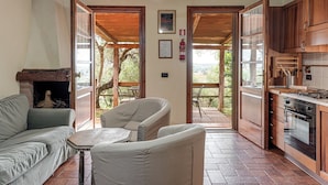 Un espacio de sala acogedor con chimenea, un sofá, una mesa y vistas al exterior.