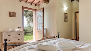 Un dormitorio con cama, cómoda, ventana y puerta que da a un balcón.